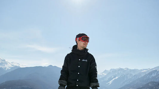 Man wearing black snow bibs and goggles in snowy mountains