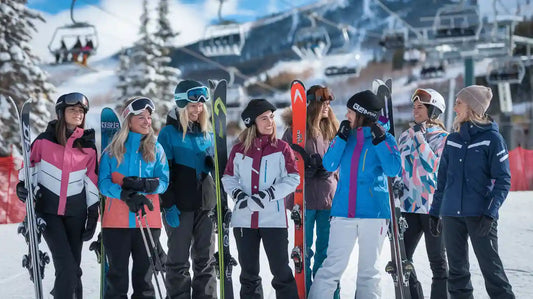 Group of women in affordable colorful ski jackets and gear, posing on a snowy slope.