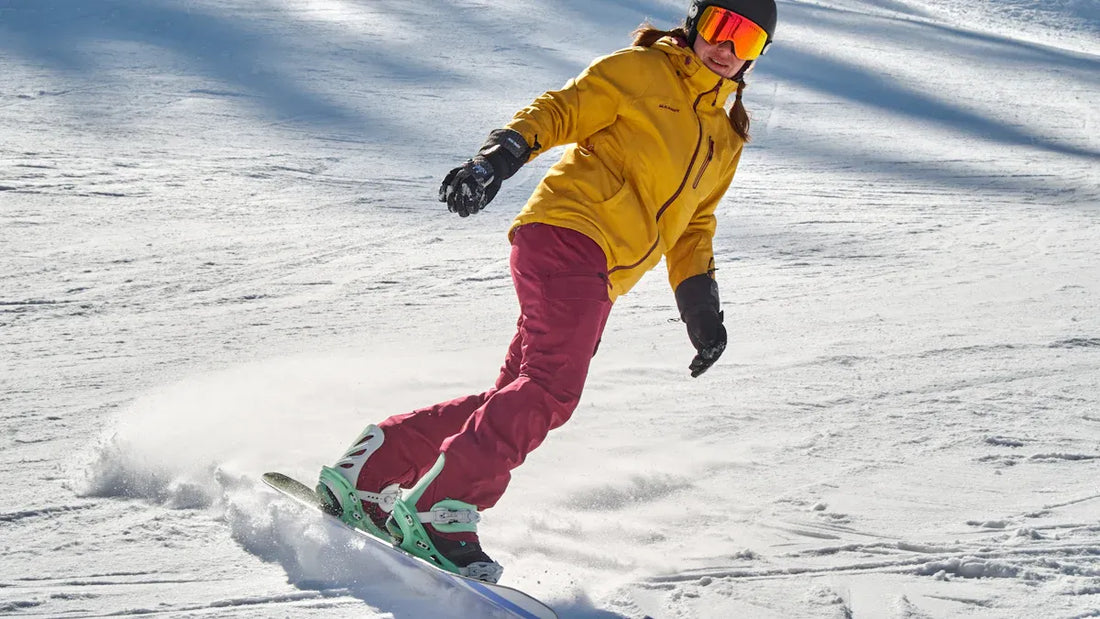 Woman snowboarding in yellow jacket and pink pants