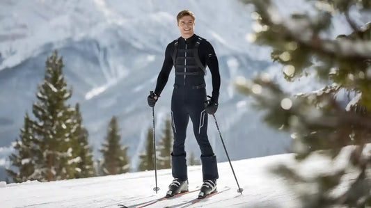 Man skiing in snow wearing black ski gear for cross-country skiing.