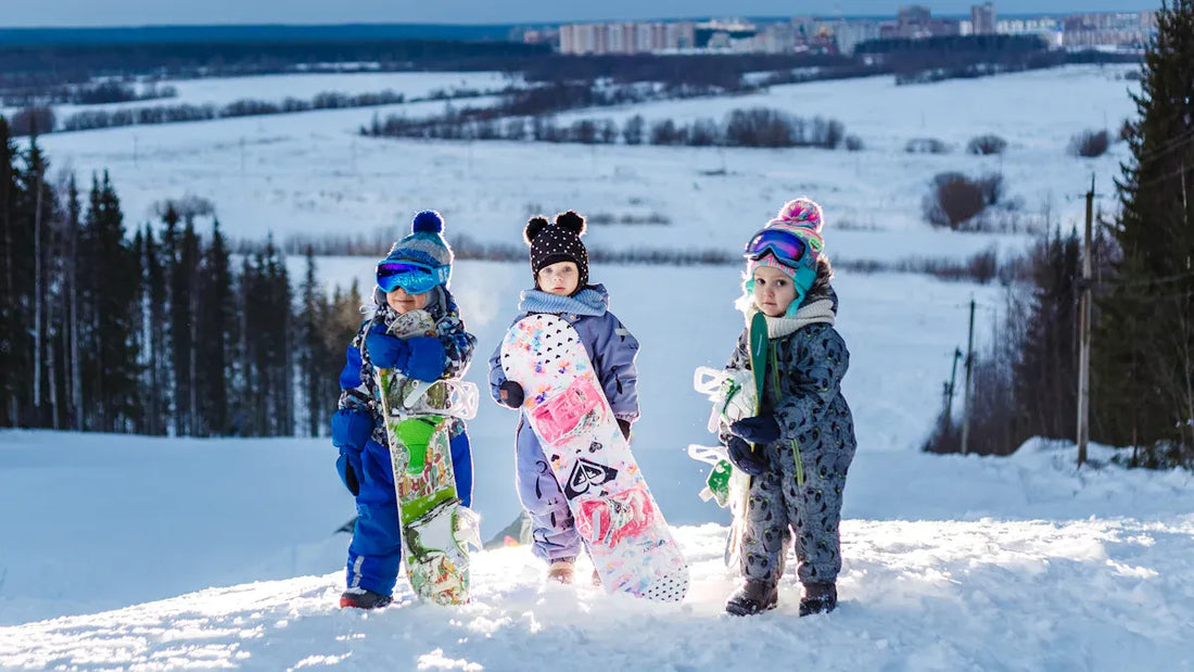 Group of kids with snowboards on a snowy hill, ready for adventure.