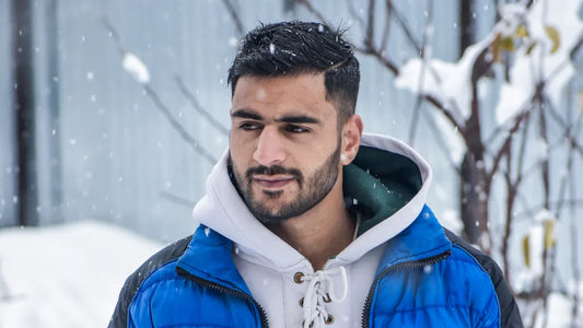 Man in a blue winter jacket standing outdoors in the snow