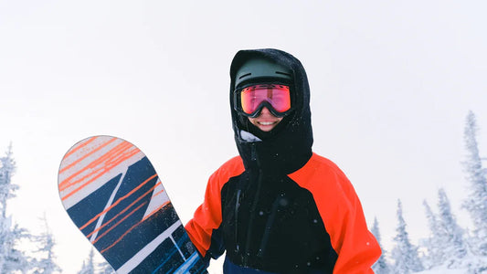 Spring skiing gear: person in colorful jacket and goggles with snowboard.