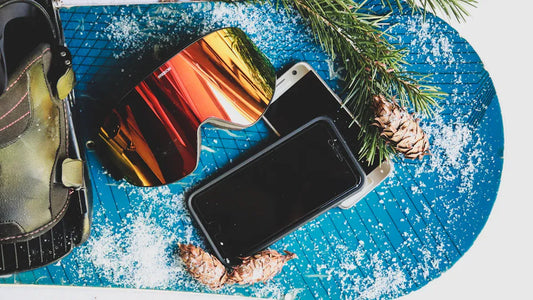 "Close-up of ski accessories like goggles and phone on snowboard