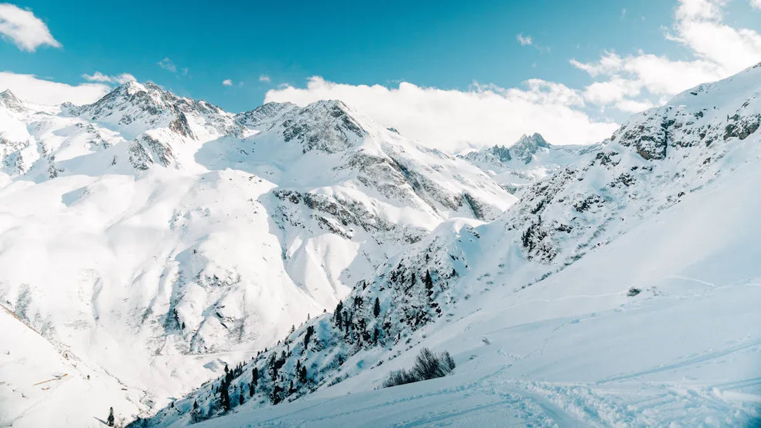 Snowy mountain landscape with towering peaks and blue sky, perfect for skiing.