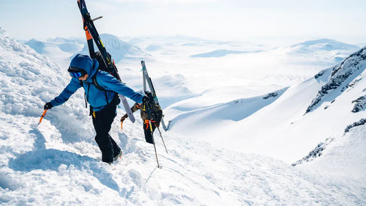 Man wearing blue ski gear while climbing snowy mountain