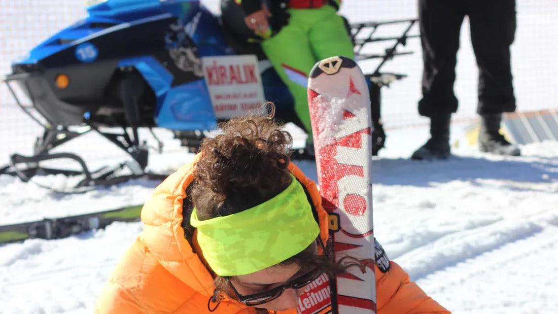 Person skiing in an orange jacket with yellow headband and skis