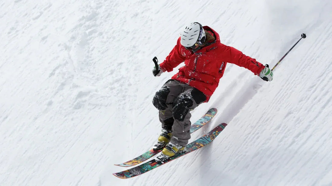 Skier wearing a red jacket skiing down a snowy slope.