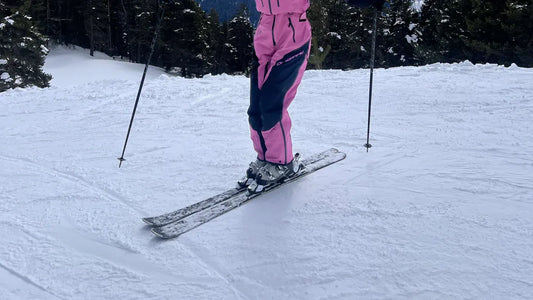 Pink and black ski bibs worn by a skier on snowy terrain, perfect for skiing.