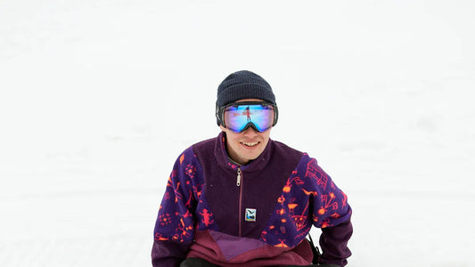 Snowboarder in purple fleece and ski goggles.