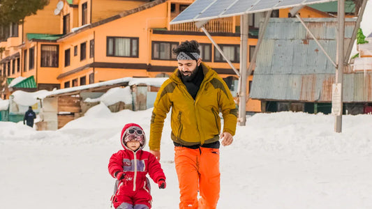 Father and child walking together in snowy mountains in ski jackets